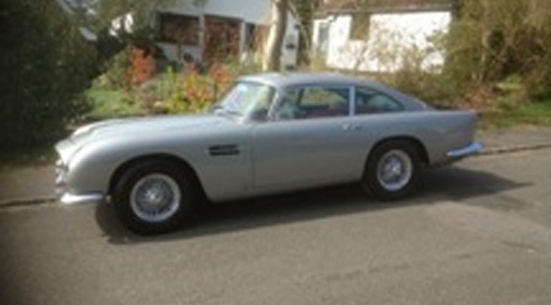 silver classic car on the side of the road in front of a house