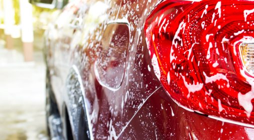 a red car that is being washed with soap suds on it