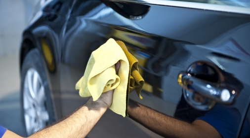 Man polishing black car with yellow cloth