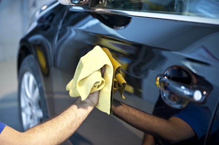 Man polishing black car with yellow cloth