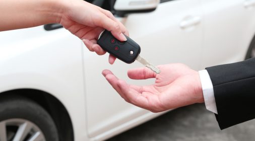 female hand giving a key for a buyer or rental car