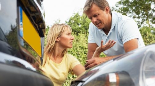 two people arguing with two cars in front of them that have crashed