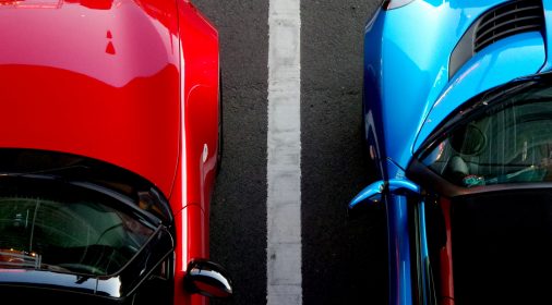 two cars parked next to each other in a car park seperated by a white line, taken from above