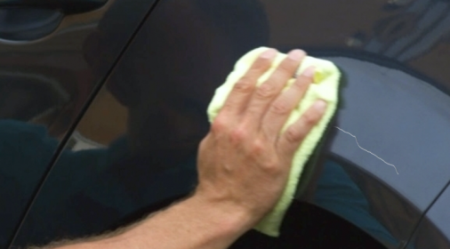 a man repairing a black car that has a scratch on it