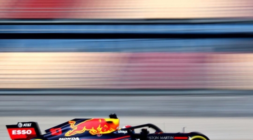 black and red race car on track with redbull logo, background blurred