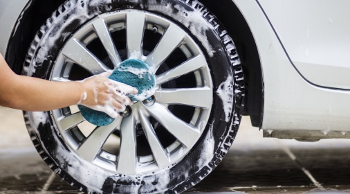 cleaning the cars alloy wheels with a blue cloth and soap.