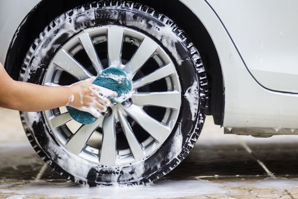 cleaning the cars alloy wheels with a blue cloth and soap.