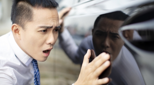 young business man watching scratched hire car