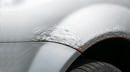 Silver car broken side with damaged metal with rusty paint and corrosion above the tire