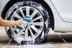 This image is a picture of wiping the car with a blue microfiber cloth by hands.Car wash concept. alloy wheel