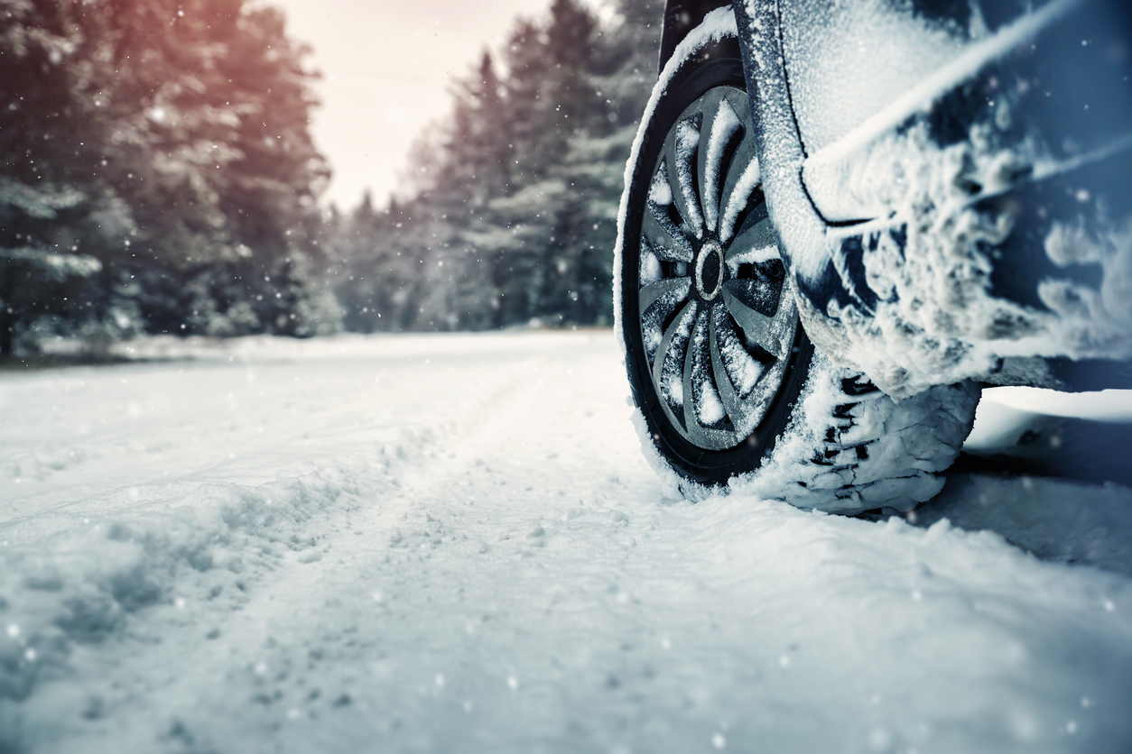 Car tires on winter road covered with snow. Vehicle on snowy way in the morning at snowfall