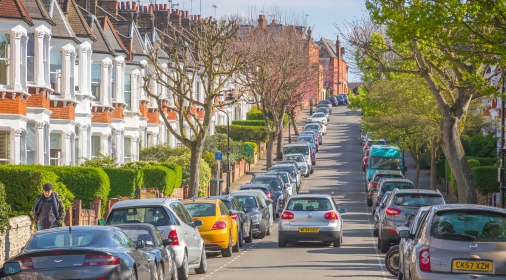 London, UK - 10 April, 2019 - A car driving through a London street lined with terraced houses and parked cars around Crouch End area