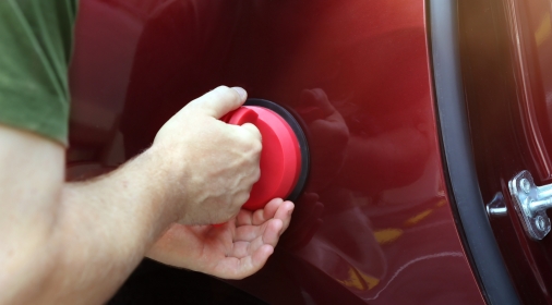 Man fixing car dent by himself with dent puller