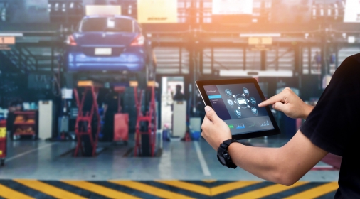 Mechanic using digital tablet Inspecting the Vehicle with auto repair shop as background