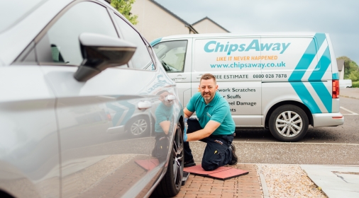 ChipsAway mobile repair specialist completing a car body repair on a silver car, on customer's driveway