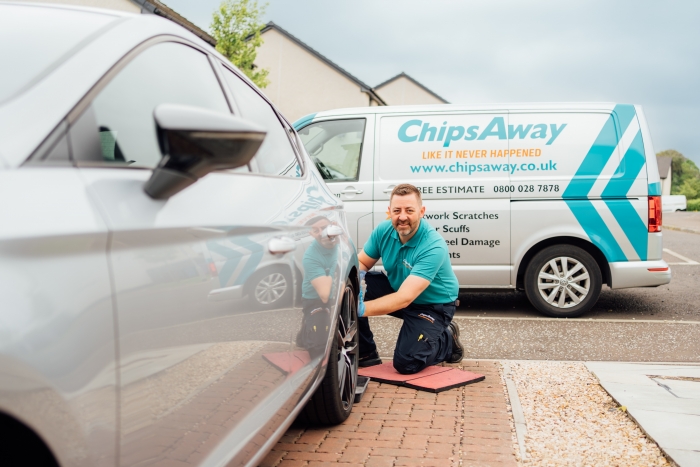 ChipsAway mobile repair specialist completing a car body repair on a silver car, on customer's driveway